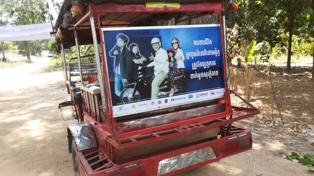 A tuk tuk panel with the message, "Protect your passengers' lives. Make sure they wear helmets." is driven throughout the commune