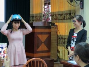 A teacher (left) demonstrates how to properly wear a motorcycle helmet.