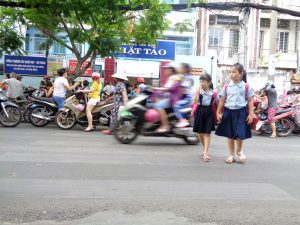 Two students cross a busy road on their way to school in Ho Chi Minh City.