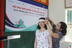 A teacher practices measuring helmet size using a paper ruler. 